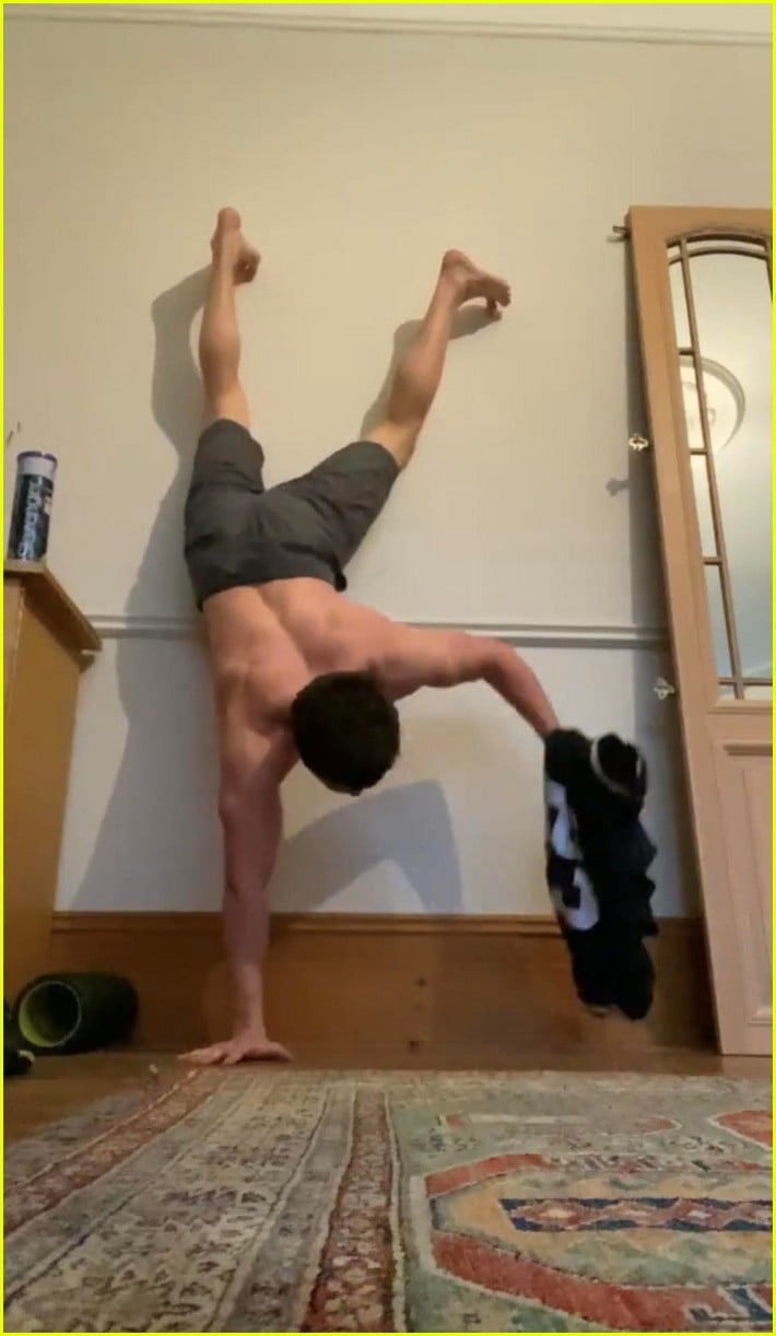 tom holland shows off muscular body while putting on a shirt while doing handstand 04