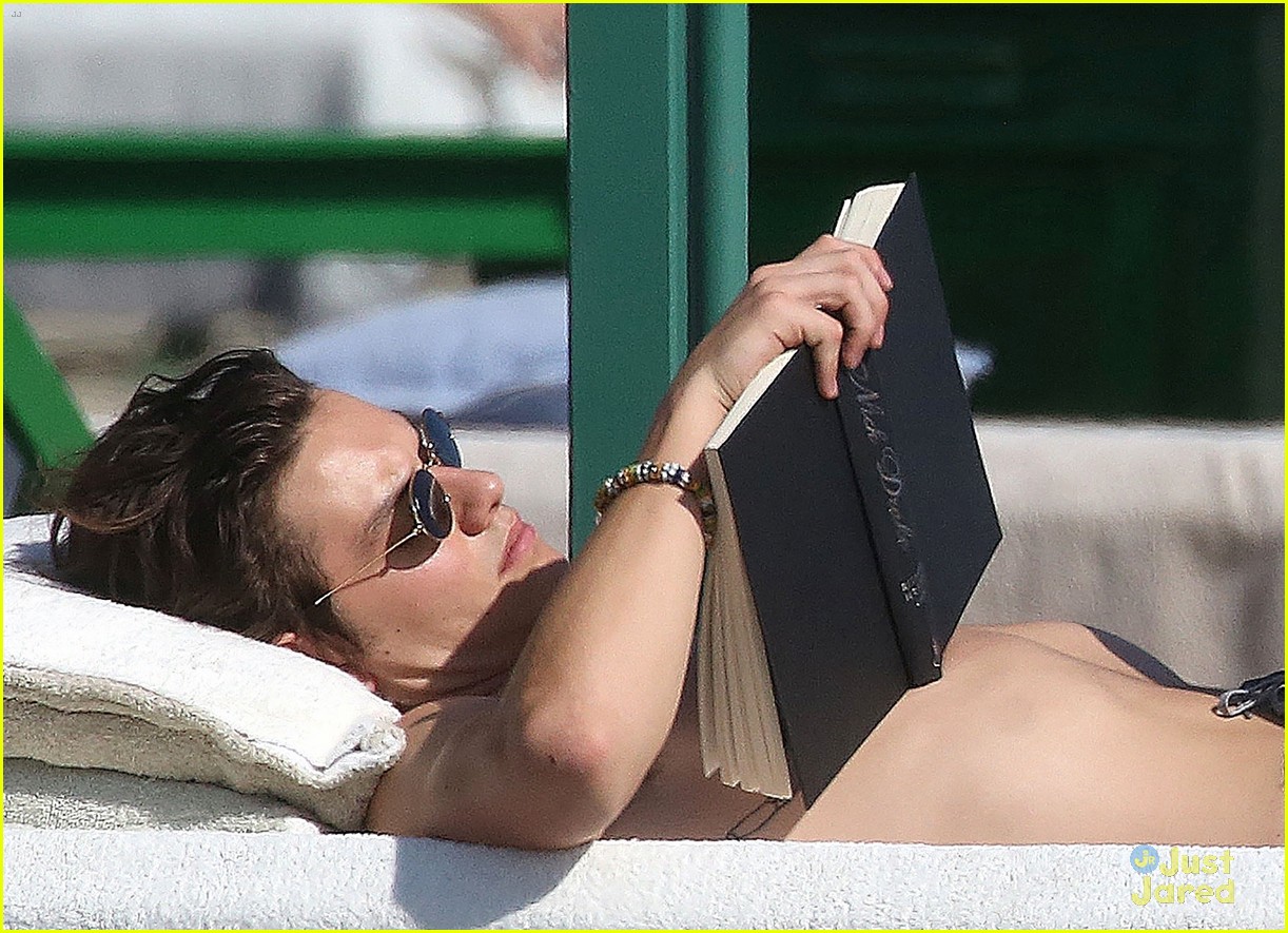 Louis Partridge goes for a dip in the water and reads a book on